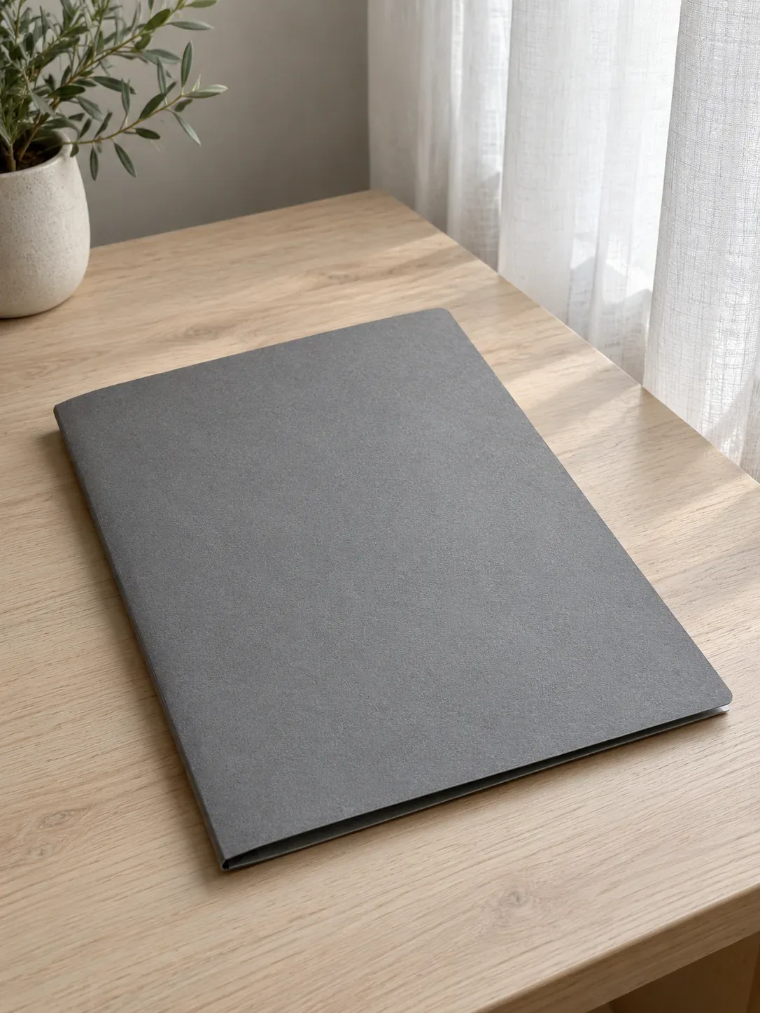 Dossier fermé sur une table près d’une fenêtre voilée.